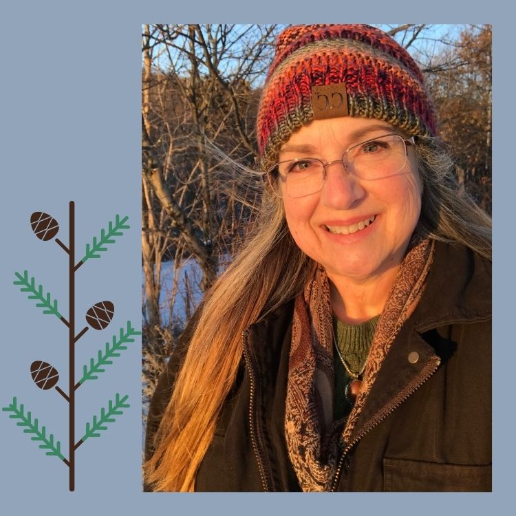 Photo of Synthia Marsh in the sunshine wearing a multi-colored winter hat and brown winter coat. During a beautiful winter day in Michigan's Upper Peninsula, in the Keweenaw Peninsula.