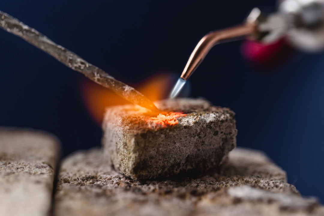 A lit soldering torch on a metalsmith's bench.